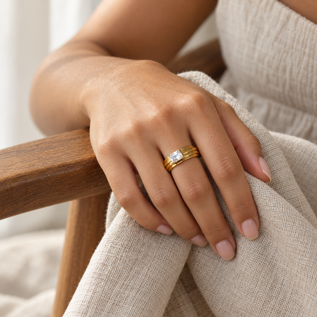 Pierścionek z prostokątnym kamieniem i żłobieniami — zdjęcie na osobie, kadr bez twarzy, wykończenie w kolorze złota.