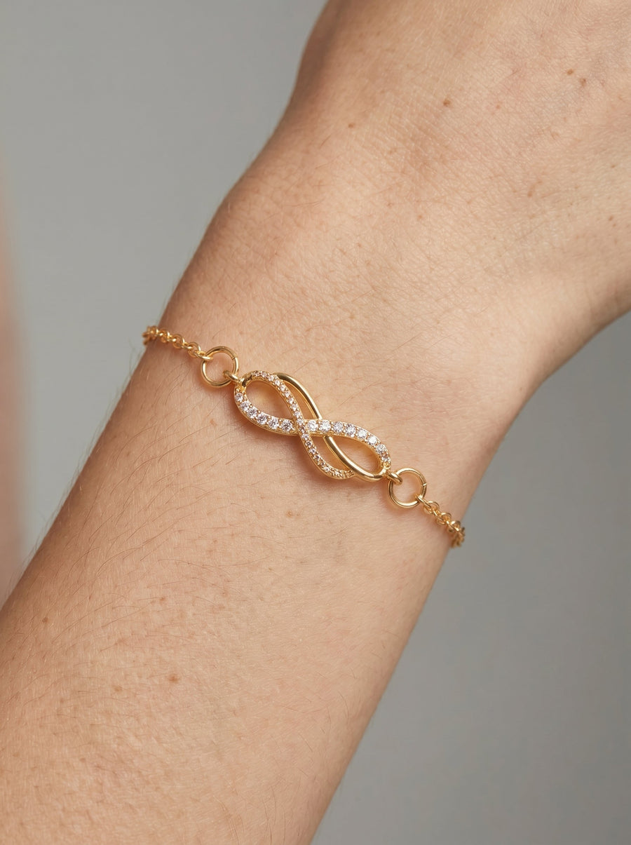 Delikatna złota bransoletka z symbolem nieskończoności, kryształkami i cienkim łańcuszkiem na nadgarstku