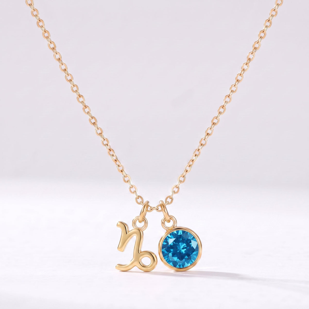 Złoty naszyjnik ze znakiem zodiaku Koziorożca i niebieską cyrkonią.